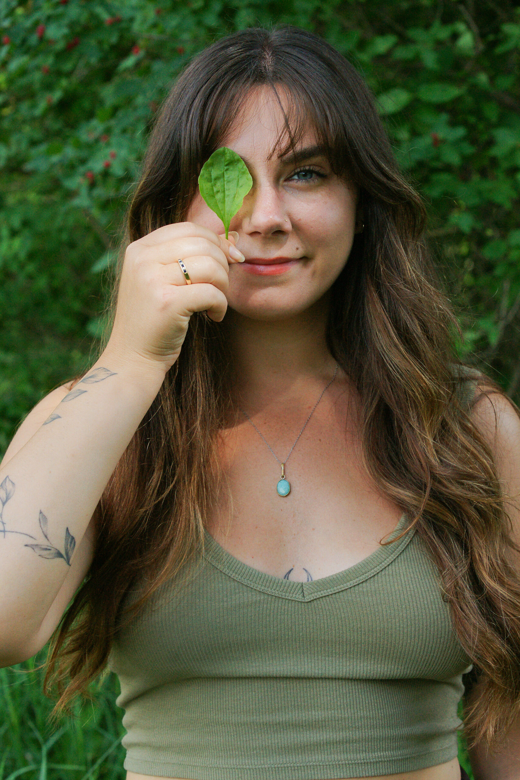 woman covering her eye with a plant leaf