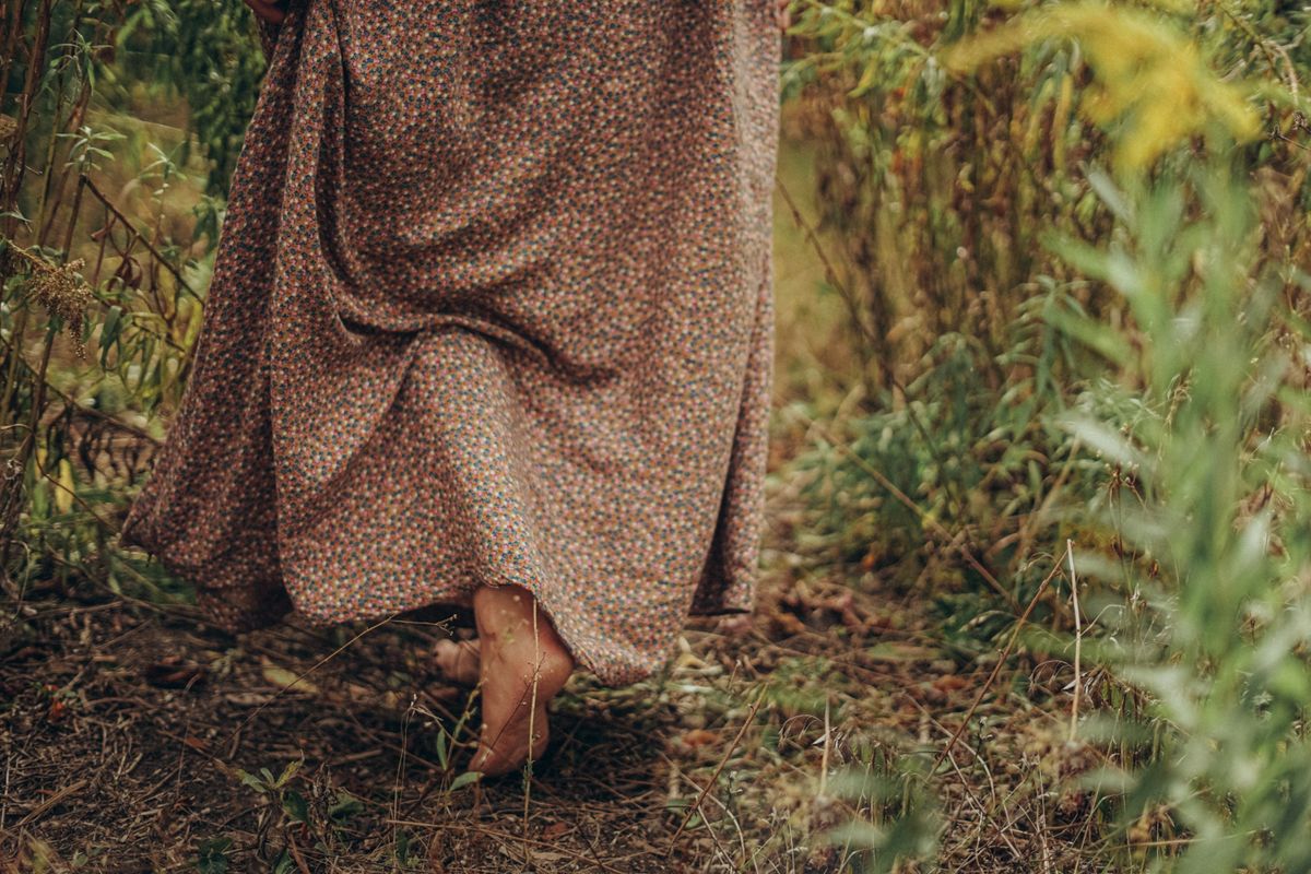 woman in a skirt walking barefoot in the grass