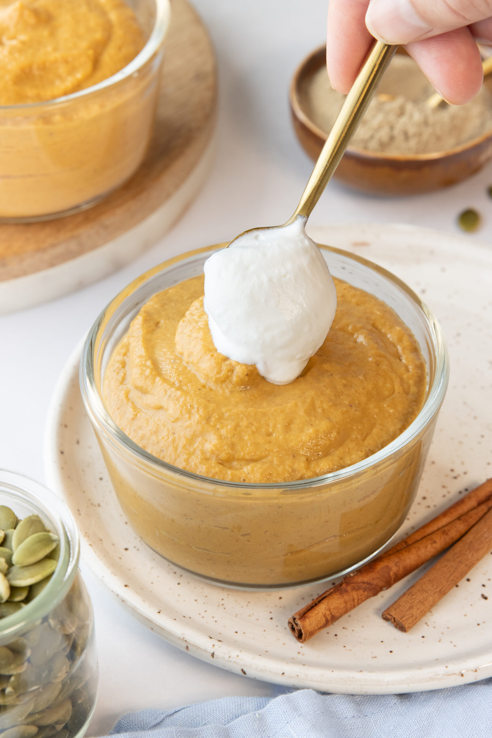 placing whipped cream on top of a bowl of pumpkin pie pudding