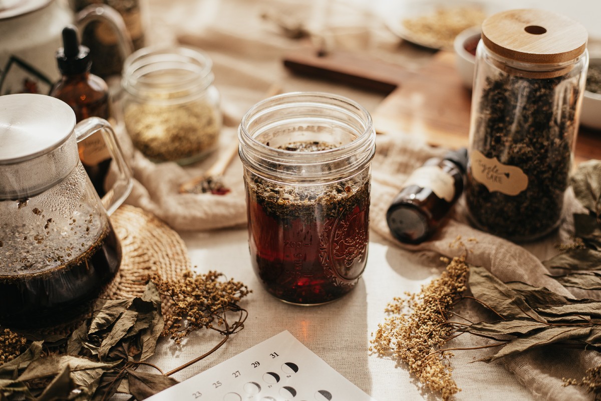 jar of tea surrounded by jars of herbs and a teapot